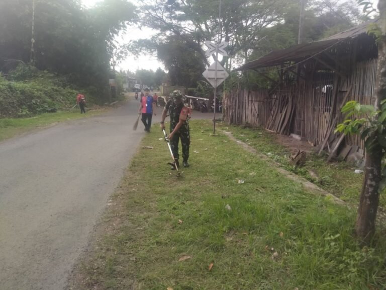 Babinsa Koramil Rogojampi Gandeng Warga Timurejo Bersihkan Rumput Liar di Bahu Jalan